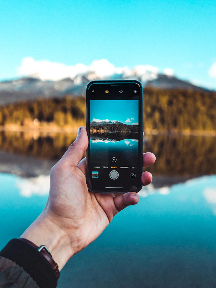 Dłoń trzymająca telefon z widokiem na górskie jezioro